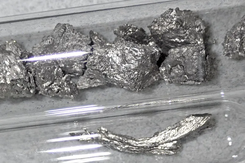 Trozos de disprosio metálico en un vial