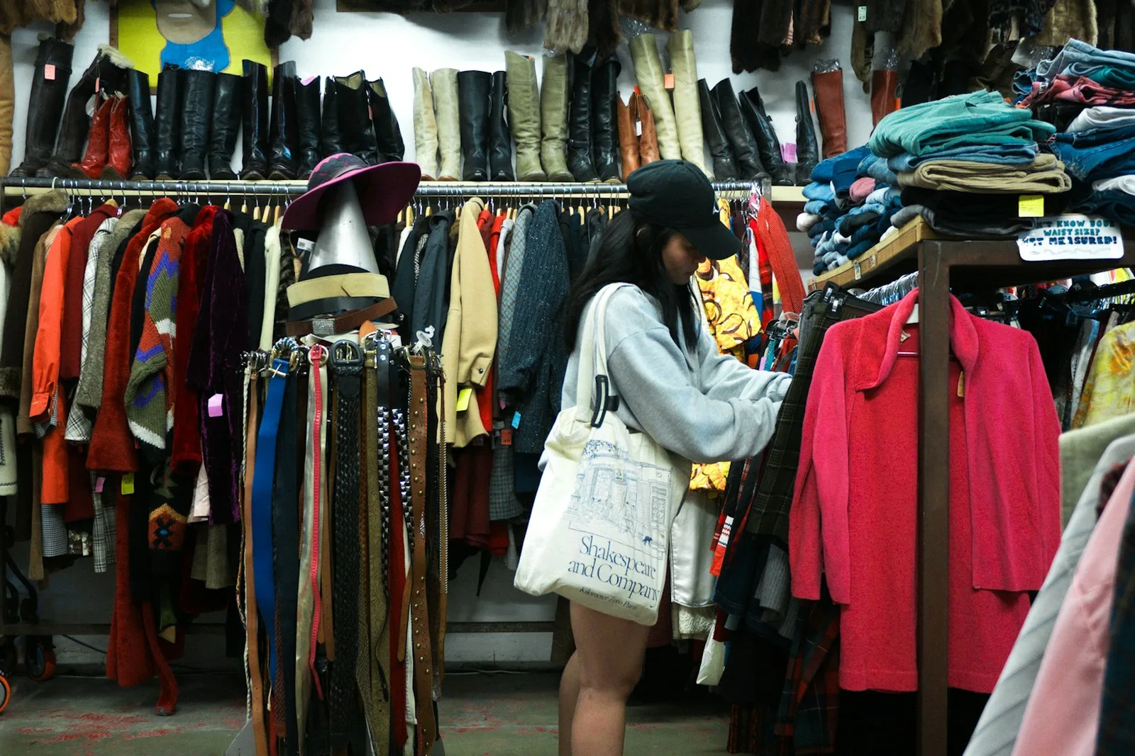 Una mujer mirando ropa colgada en las perchas de una tienda de segunda mano